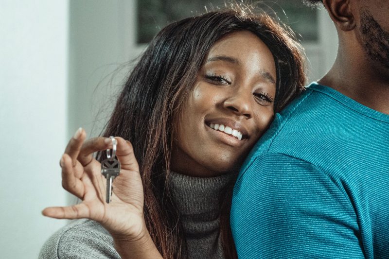 Joyful couple celebrating their new home, holding a set of keys together with smiles.